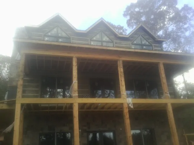 Dormers and porch framing on a large log home under construction — Roof Coating work by our crew in Pineola