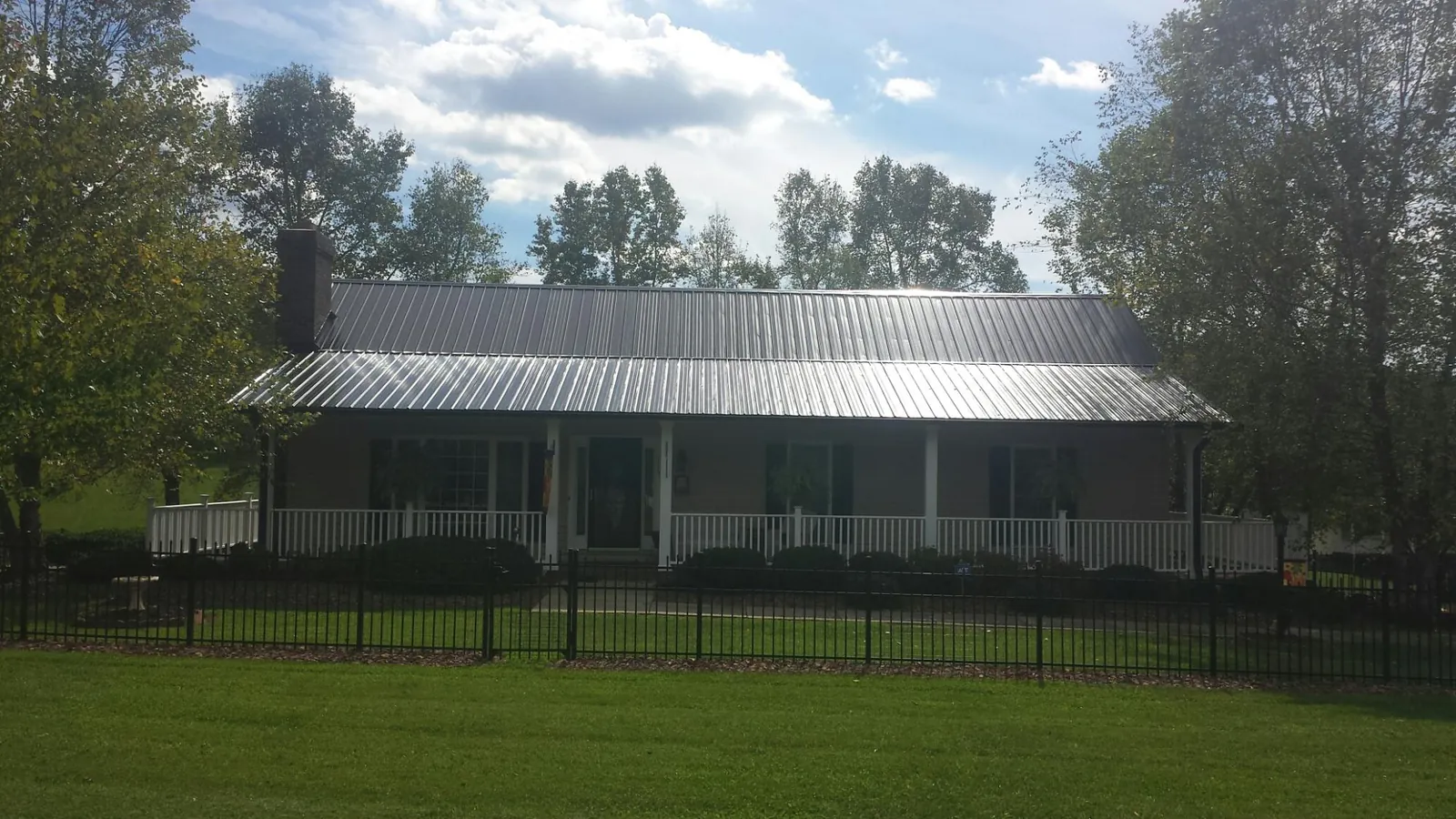 Gray metal roof on a brick ranch with a full width front porch — Gutter Guard Installation work by our crew in Pineola
