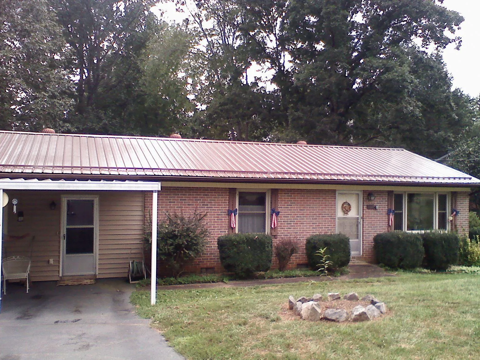 Bronze metal roof and carport on a brick ranch home — Roof Repair work by our crew in Pineola