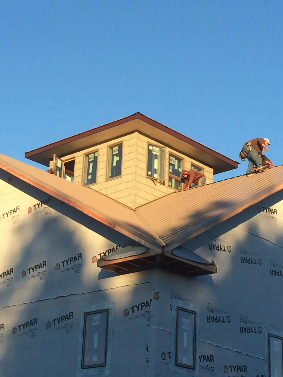 Roofers working around a rooftop cupola on a new metal roof at sunset — Roof Waterproofing in Pineola by Roofing Brothers